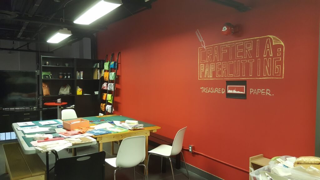 Workshop space for Papercraft sessions showing a bright red wall with small table and chair set up.