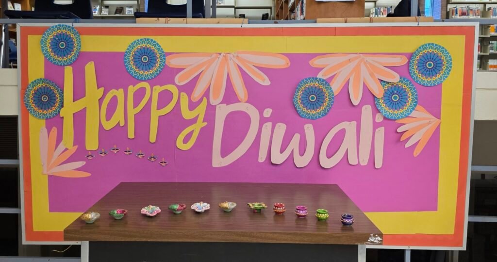 Happy Diwali display board using a mix of fireworks and flower petals and tealights to create a sense of fun and celebration. A table is placed in front of the board with some tea light holders.