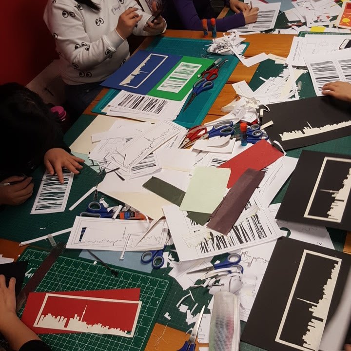One of Elaine's papercutting sessions showing students working on paper cuttings of Toronto Skyline and birch forest.